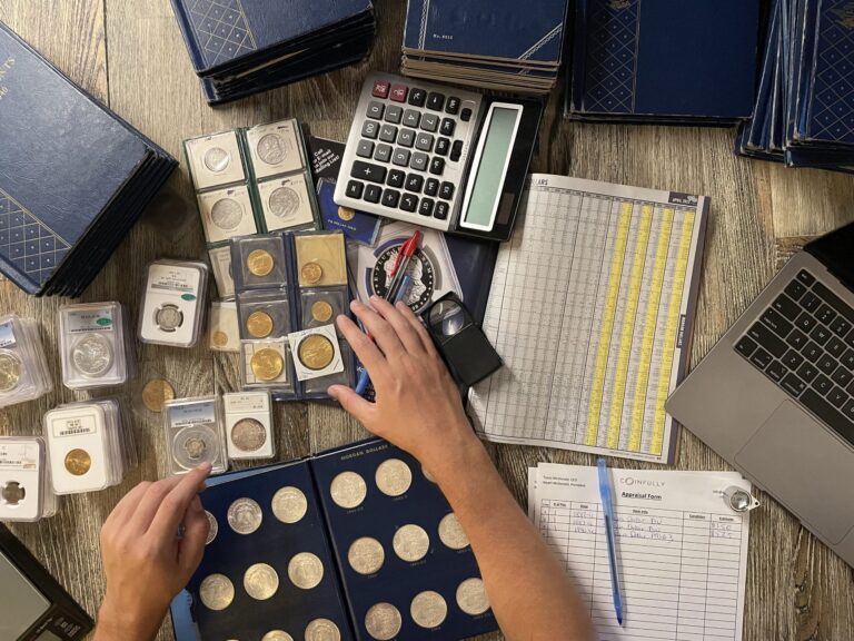 Coin appraisal scene with coins, a calculator, a laptop, and an appraisal form on a wooden table.
