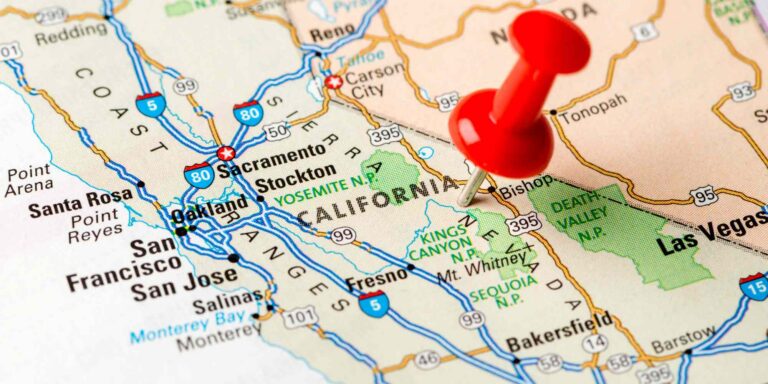 Map of the western United States with a red pushpin marking California, highlighting cities and national parks.
