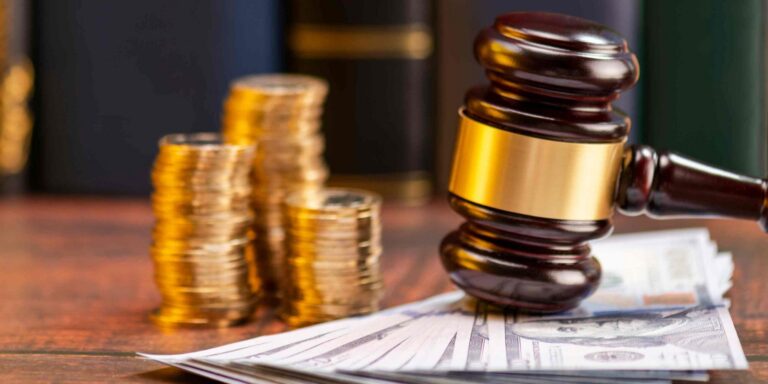 A gavel rests on a stack of cash, with gold coins in the background and books partially visible.