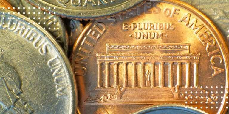 Close-up of various American coins, including a penny featuring the Lincoln Memorial and "E Pluribus Unum."