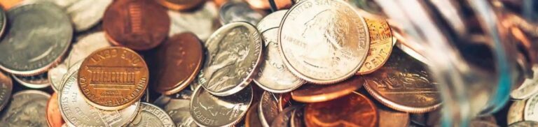 A variety of coins scattered on a surface, including pennies, nickels, dimes, and quarters.