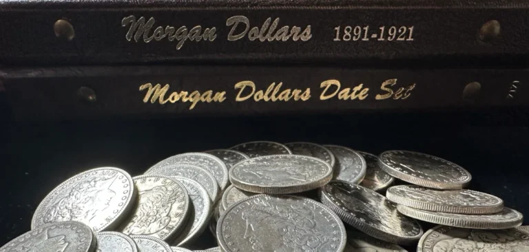 Morgan silver dollars scattered in front of two albums labeled "Morgan Dollars 1891-1921" and "Morgan Dollars Date Set."