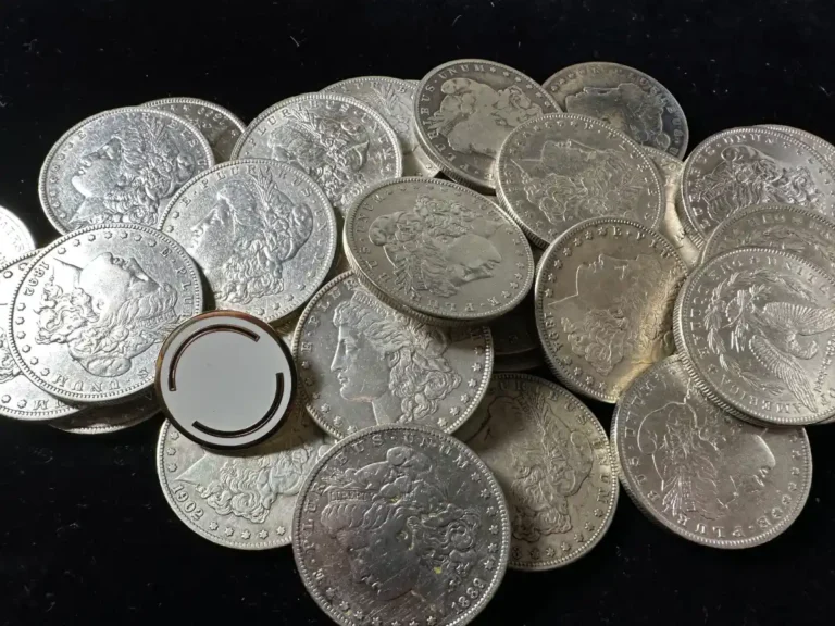 Close-up of multiple silver half dollars, showcasing their intricate designs and a white coin holder in the center.