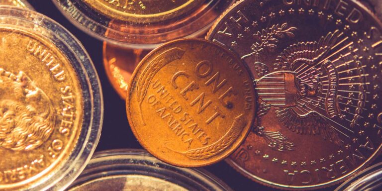 One cent coin surrounded by various other coins, showing "ONE CENT" and "UNITED STATES OF AMERICA."