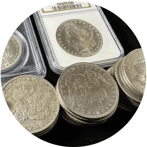 Stacks of silver coins, including a graded coin in a protective case, arranged on a black surface.