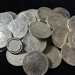 A pile of silver coins with one coin featuring a circular cutout in the center.