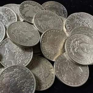 A pile of silver coins featuring various historical designs and details.