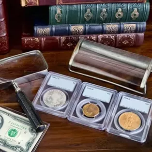 Graded collectible coins, paper money, and magnifying glass on a wooden table.