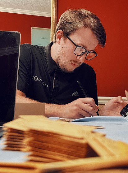 Wyatt McDonald appraising coins while writing notes