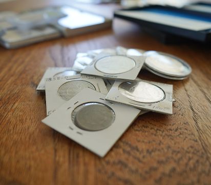 A pile of coin holders with various coins on a wooden surface.