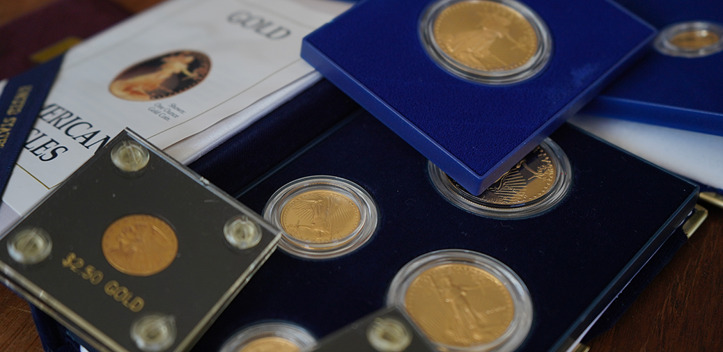 Gold coins displayed in protective cases, with a booklet titled "Gold"