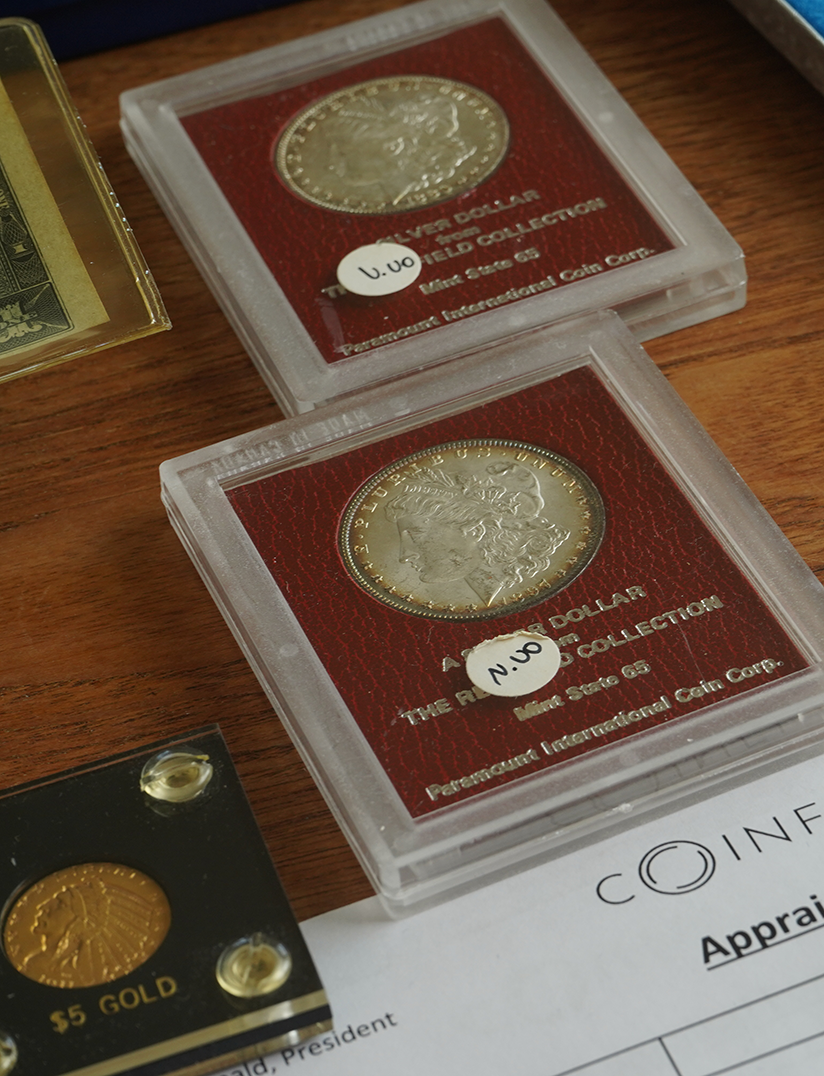 Two silver coins in protective cases on a wooden surface