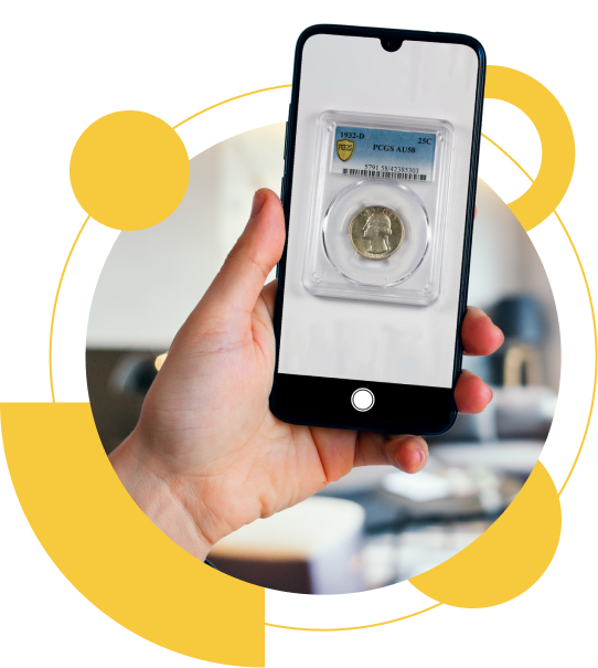A hand holding a smartphone displaying a graded coin in a protective case