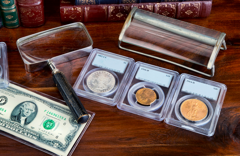 Graded coins displayed in protective cases with a magnifying glass
