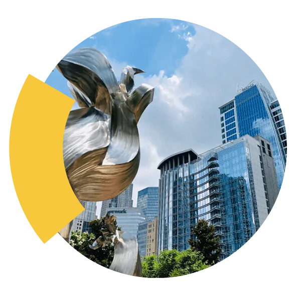 Metallic abstract sculpture in front of glass skyscrapers